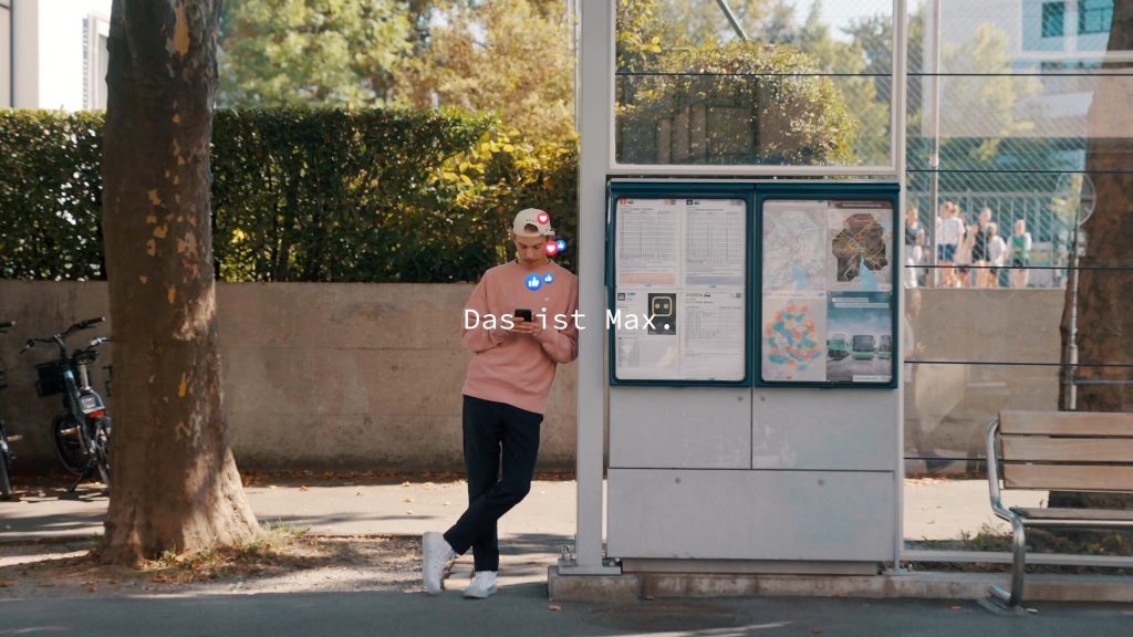 Das Standbild des Gewinnervideos zeigt einen Mann an der Bushaltestelle, der auf sein Smartphone schaut.